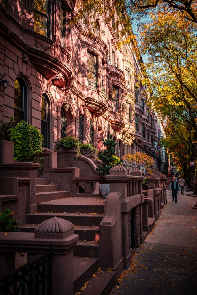 Historic brownstone townhouses with stoops on a tree-lined New York City street in autumn